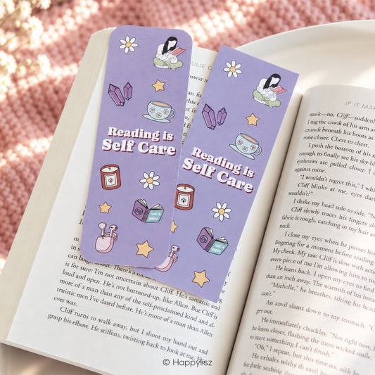 Two matching lavender bookmarks with rounded corners, featuring the phrase 'Reading is Self Care' in white text and cute illustrations of a person reading, flowers, crystals, a cup, books, stars.